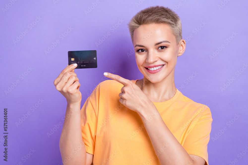 Photo of cheerful gorgeous person toothy smile indicate finger hand hold debit card isolated on violet color background Photo of cheerful gorgeous person toothy smile indicate finger hand hold debit card isolated on violet color background