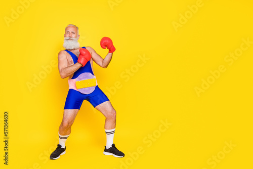Full length photo of serious funky senior guy wear blue overall costume boxing champion empty space isolated yellow color background © deagreez