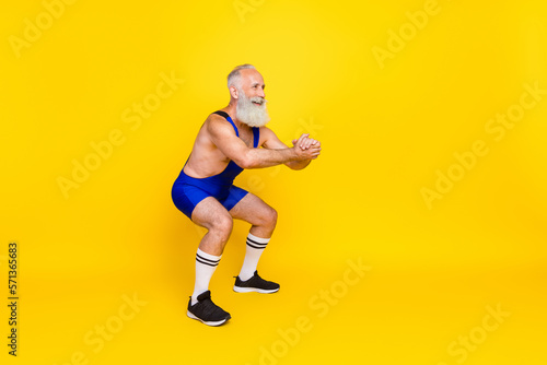 Photo of active energetic sportive retired man war overall sitting up squats cardio look empty space isolated on yellow color background © deagreez