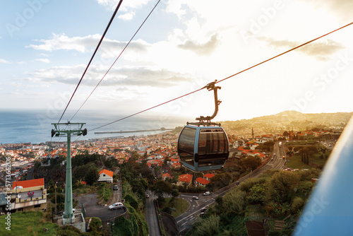 Beautiful landscape of the city of Funchal with cable cars, orange roofs and the ocean at sunset. Traveling on the island of Madeira
