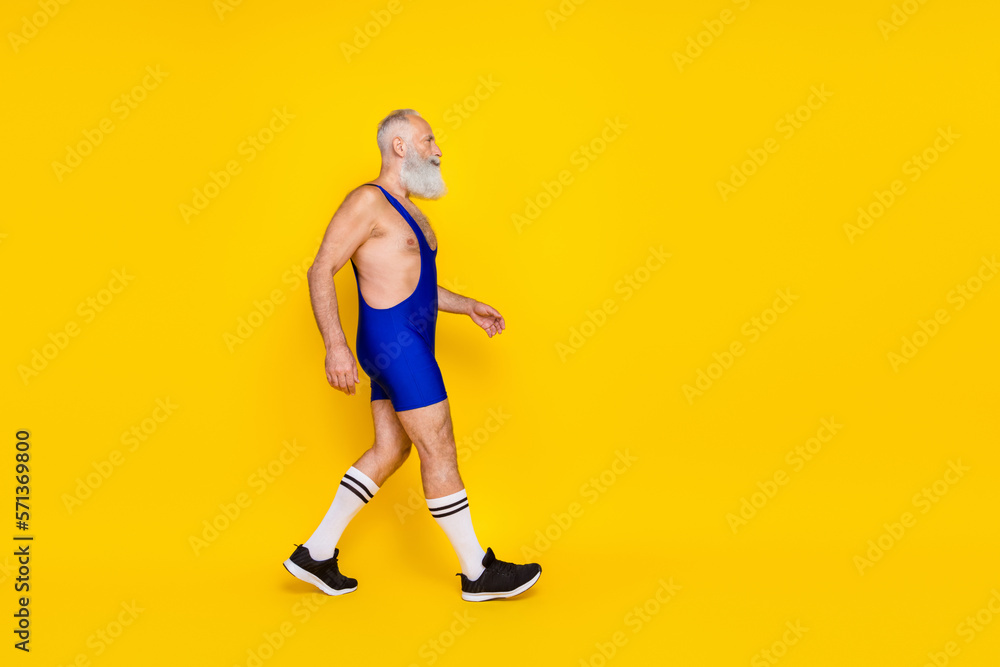Full length profile photo of sportive aged man walking look empty space isolated on yellow color background