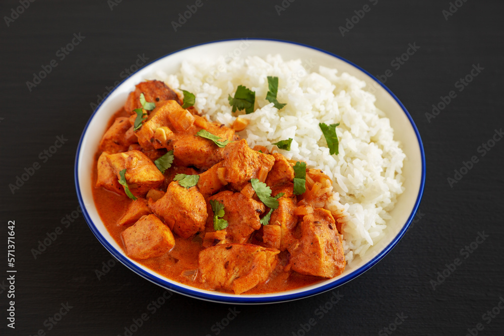 Homemade Easy Indian Butter Chicken with Rice on a Plate on a black background, side view. Close-up. Homemade Easy Indian Butter Chicken with Rice on a Plate on a black background, side view. Close-up.