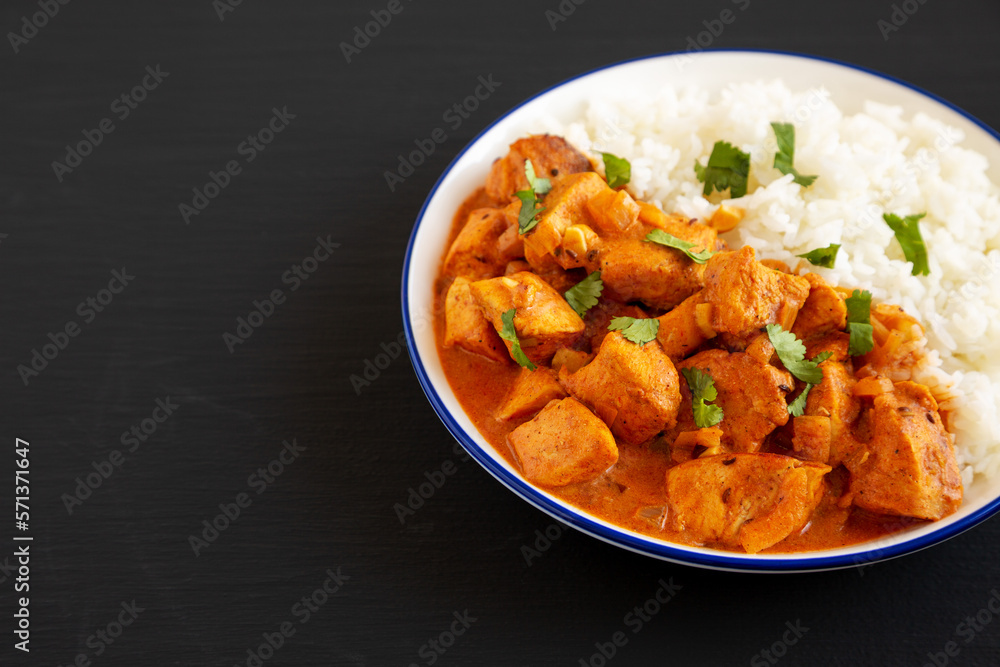 Homemade Easy Indian Butter Chicken with Rice on a Plate on a black background, side view. Space for text.