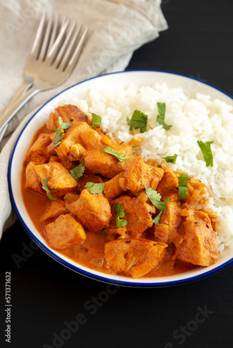 Homemade Easy Indian Butter Chicken with Rice on a Plate on a black background, side view. Close-up.