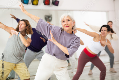 Group of adult people practices dance aerobics in class in the dance studio