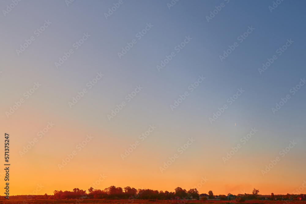 Sunset on the clear sky with blue, orange and red colors. Color gradient of the morning sky. Beautiful bright sunrise on the sky, background.