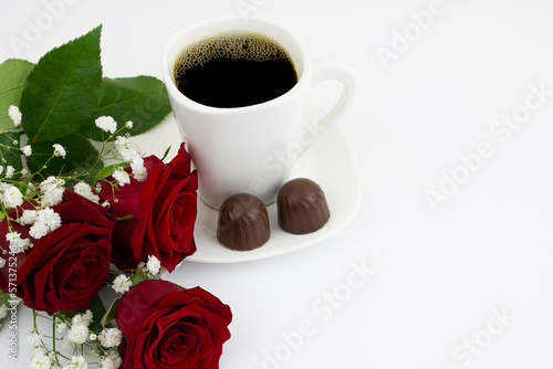 Coffee with sweets and a bouquet of red roses on a white background. Copy space.