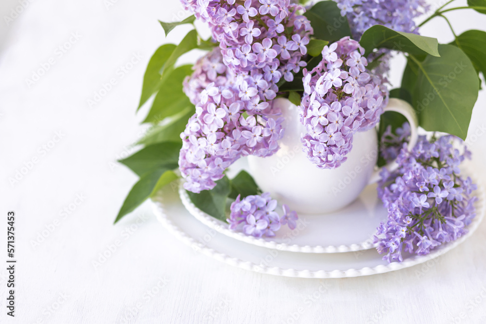 Obraz premium Beautiful spring composition with lilac flowers in a white cup for countryside decor. Greeting card for Mother's or Women's Day, anniversary or birthday
