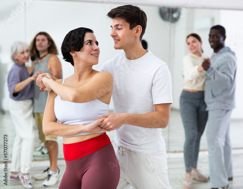 Happy caucasian guy and girl practising paired latin dance in dance studio