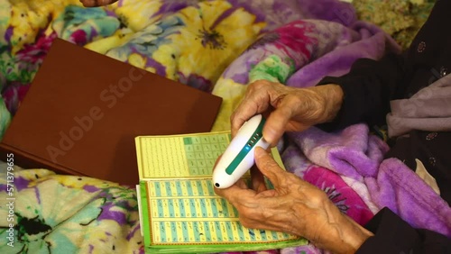 Elderly woman at home use electric Koran read pen to read in arabic photo