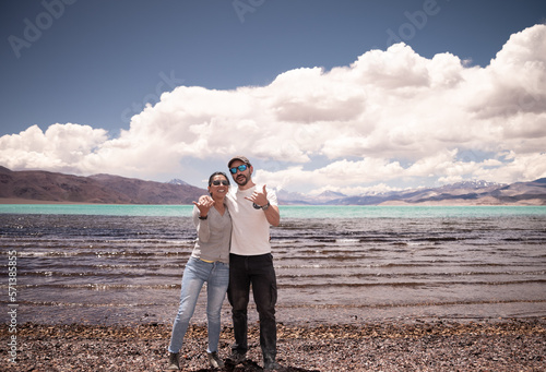 pareja de enamorados disfrutando vacaciones en cordillera de los andes junto a laguna color turquesa