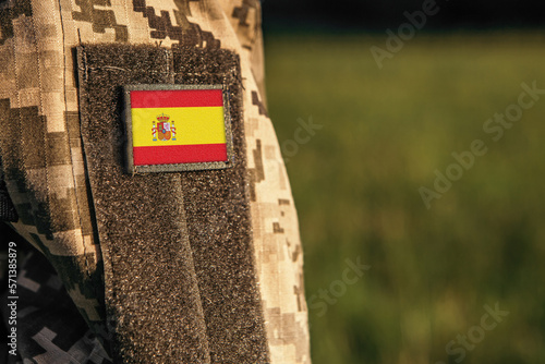 Close up millitary woman or man shoulder arm sleeve with Spain flag patch. Spain troops army, soldier camouflage uniform. Armed Forces, empty copy space for text
