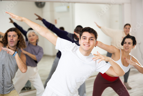 Smiling dark-haired young guy attending group choreography class  learning modern dynamic dances. Concept of active lifestyle ..