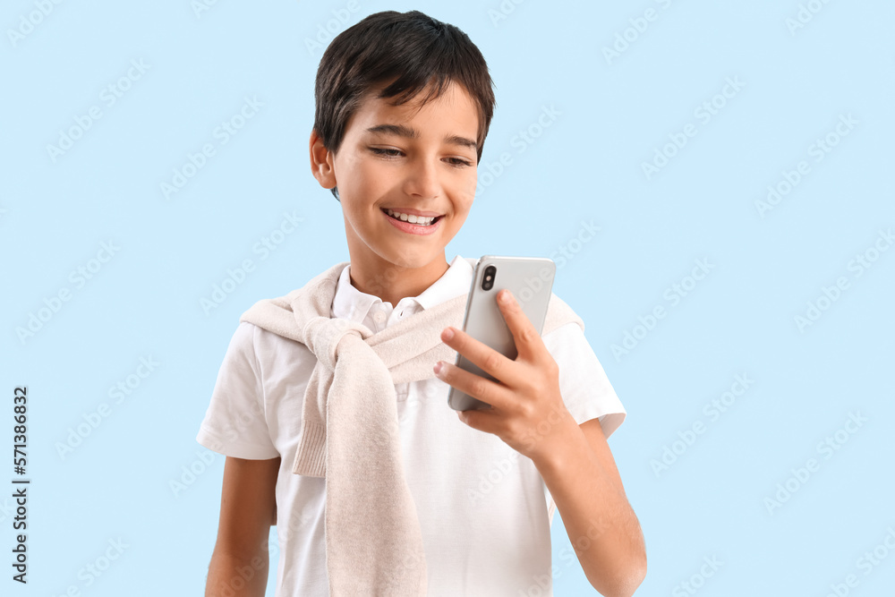 Little boy using mobile phone on blue background Little boy using mobile phone on blue background