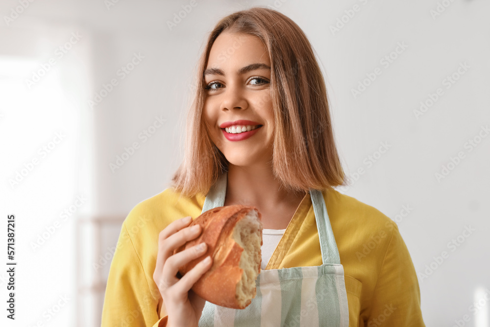 Female baker with piece of fresh bread in kitchen Female baker with piece of fresh bread in kitchen