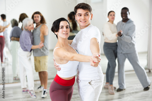 Portrait of young Hispanic woman and guy practicing in modern choreography studio  dancing slow ballroom dances in pair