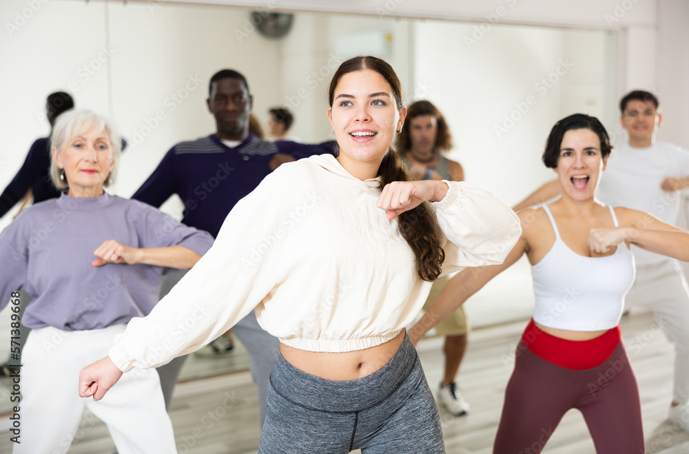 Fototapeta premium Cheerful young lady learning new modern dance in group dance lesson