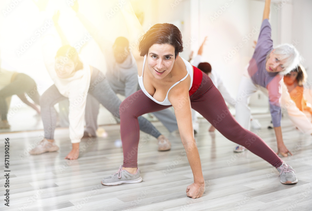 Obraz premium Active people performing a stretching exercise during a group workout in a dance studio