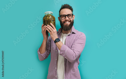 Portrait of a handsome farmer in glasses with a beard holds fresh cucumbers in a jar in his hands. Pickling cucumbers for the winter. Salted cucumbers.