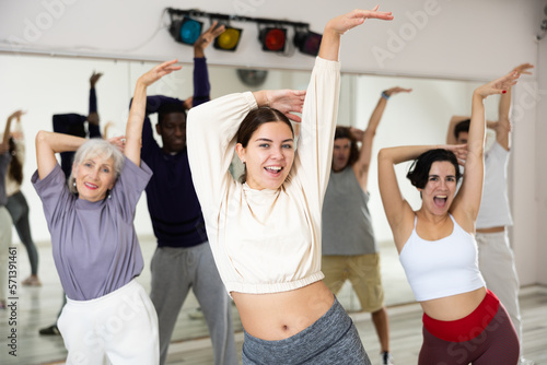 Smiling attractive young girl enjoying latin dances in modern studio, practicing passionate bachata during group class