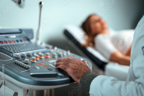 Sonographer using ultrasound machine at work. Modern clinical diagnostics and treatment. Close-up ultrasound scanner in hand of doctor. Doctor ultrasound examine female patient abdomen at hospital