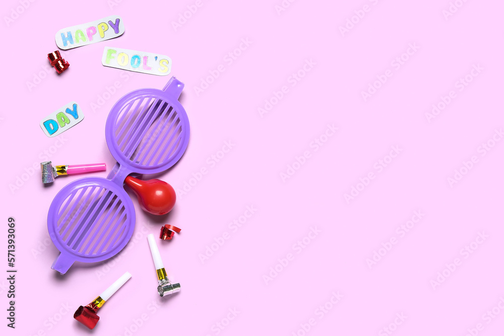 Text HAPPY FOOL'S DAY, funny disguise and party blowers on pink background