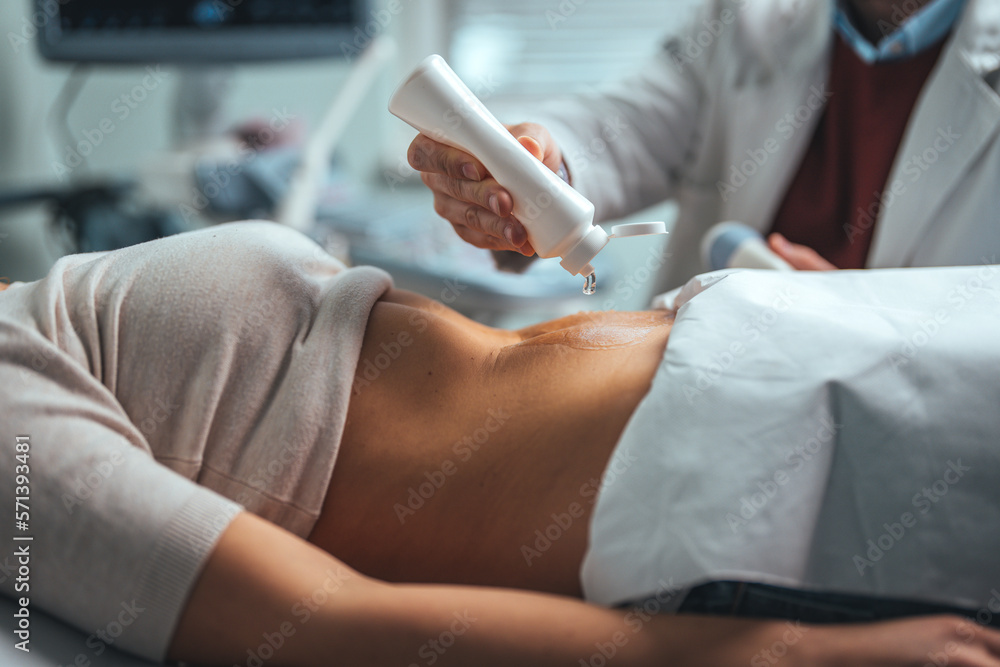 Fototapeta premium Gynecologist doctor does ultrasound, sonogram procedure to a pregnant woman. Doctor makes the patient women abdominal ultrasound. Ultrasound Scanner in the hands of a doctor. Diagnostics. Sonography