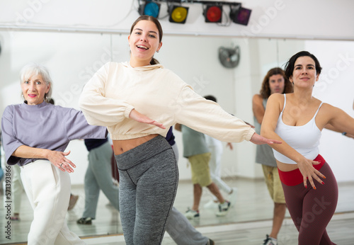 Fototapeta Naklejka Na Ścianę i Meble -  Energetic sporty young girl practicing modern vigorous dance movements in group dance class ..