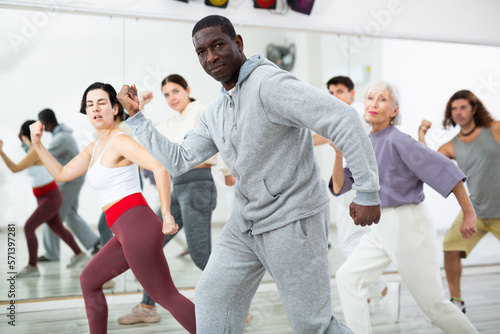 Group of dancing people practice synchronized choreography in a dance studio in the lesson