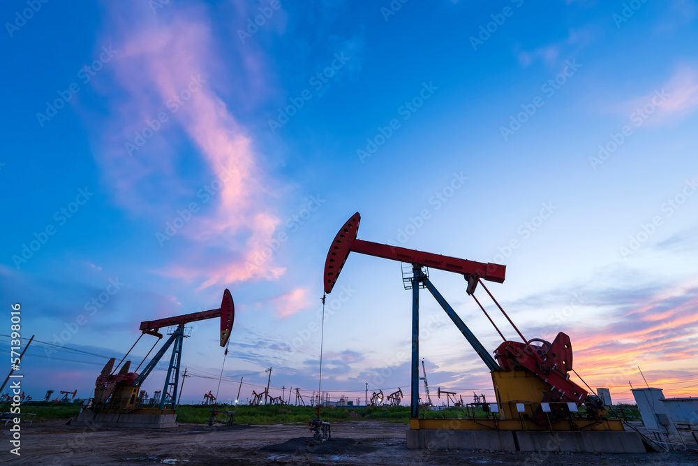 in the evening, oil pumps are running, The oil pump and the beautiful sunset reflected in the water, the silhouette of the beam pumping unit in the evening. in the evening, oil pumps are running, The oil pump and the beautiful sunset reflected in the water, the silhouette of the beam pumping unit in the evening.