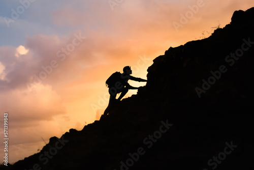Young man climbing up a mountain. Hiker winning reaching life goal, success, freedom and happiness, achievement concept. 