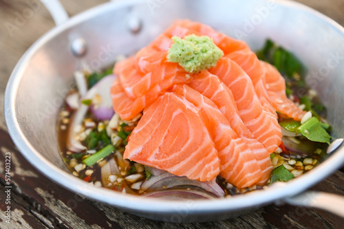 salmon fillet with wasabi on spicy sauce , fresh raw salmon salad on wooden table - Thai food
