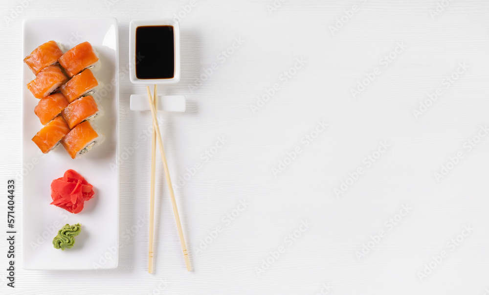 Sushi roll Philadelphia with salmon, avocado, cream cheese on white background. Sushi menu, rolls served on white dish with wasabi, ginger and soy sauce. Japanese cuisine food. Banner, copy space Sushi roll Philadelphia with salmon, avocado, cream cheese on white background. Sushi menu, rolls served on white dish with wasabi, ginger and soy sauce. Japanese cuisine food. Banner, copy space