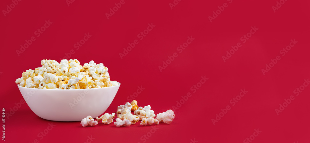 Scattered tasty cheese popcorn in bowl isolated on red background. Wallpaper, banner, header with copy space for text Scattered tasty cheese popcorn in bowl isolated on red background. Wallpaper, banner, header with copy space for text