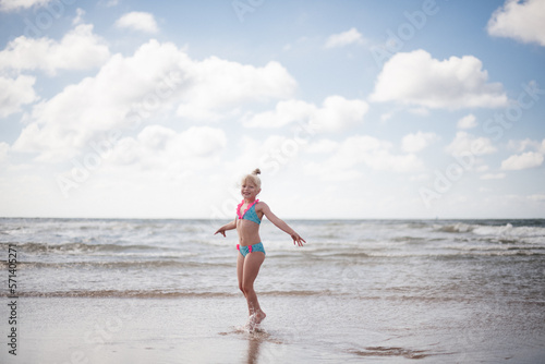 Little girl play along the beach by the sea. 