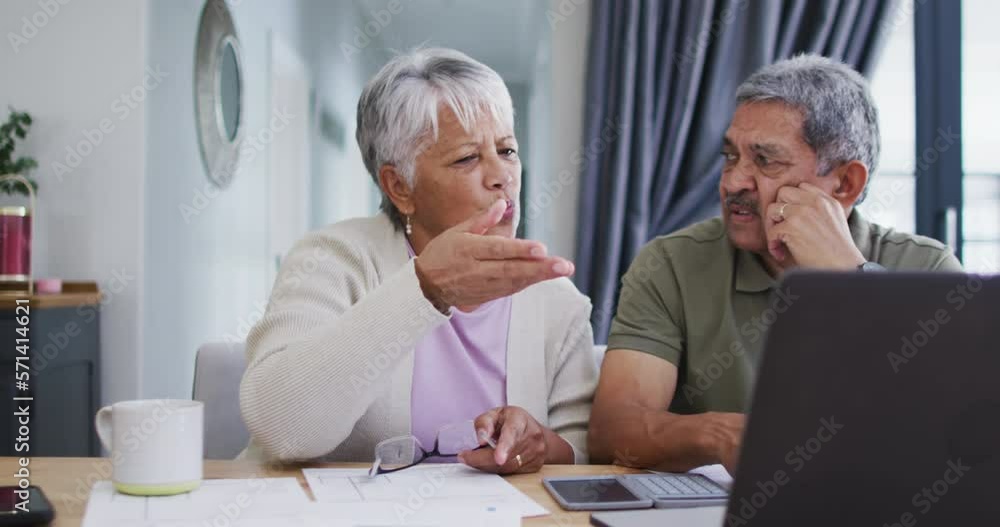 Senior biracial couple talking and using laptop Senior biracial couple talking and using laptop