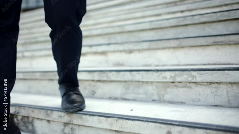 Close-up legs of businessman are hurrying to walk into the meeting to be on time a modern office in city. Employees hurry to go to work during rush hours. Close-up legs of businessman are hurrying to walk into the meeting to be on time a modern office in city. Employees hurry to go to work during rush hours.