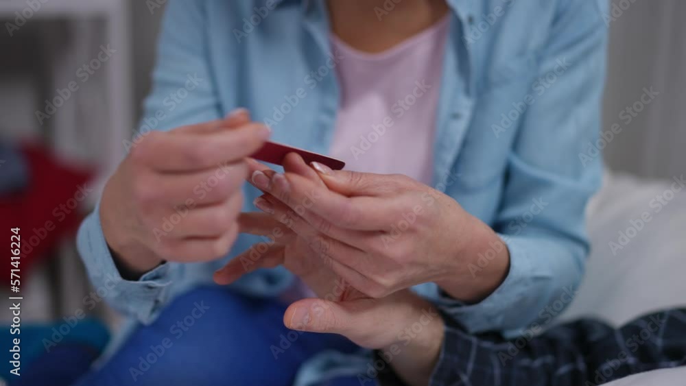 Close-up female hands filing male nails sitting on bed in bedroom. Unrecognizable Caucasian wife taking care of ill husband at home indoors. Pampering and relationship concept Close-up female hands filing male nails sitting on bed in bedroom. Unrecognizable Caucasian wife taking care of ill husband at home indoors. Pampering and relationship concept