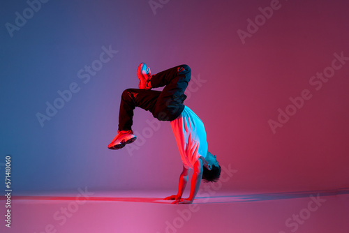 young guy dancer break dancing in neon red blue lighting  active energetic man doing acrobatic tricks  crazy moves
