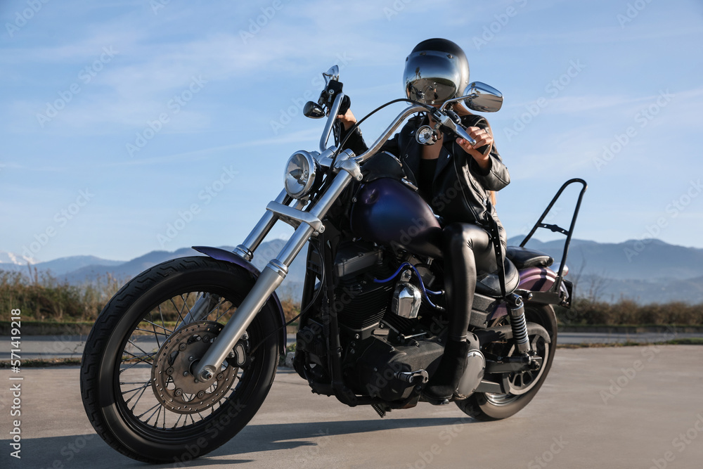Woman in helmet sitting on motorcycle outdoors