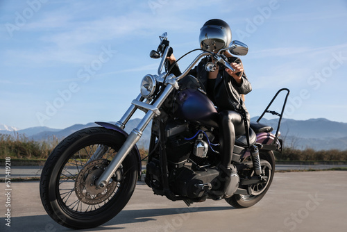 Woman in helmet sitting on motorcycle outdoors