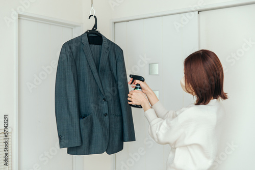 スーツに消臭スプレーをかける女性 photo