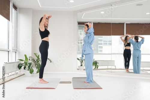 Caucasian and Asian women getting ready to stand on sadhu boards. 