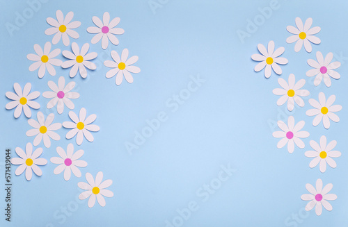 Fondo de color azul pastel con margaritas blancas de papel, ilustra la primavera en tonos pastel con paper cut