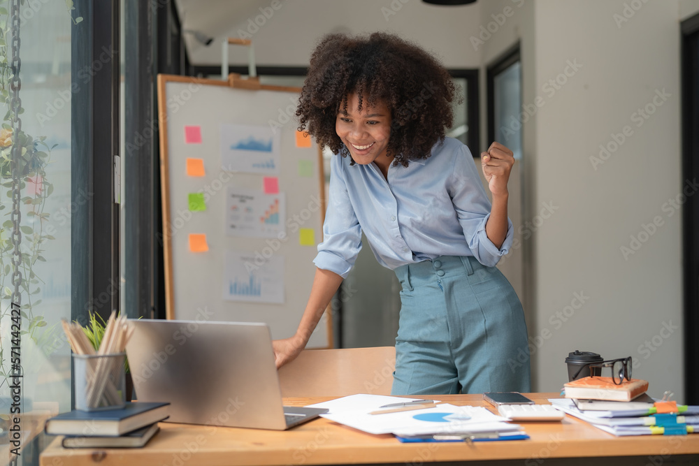 African American businesswomen celebrate winning or getting e-commerce shopping offers on computer laptops. Excited happy girl winner looking at notebook celebrating success. African American businesswomen celebrate winning or getting e-commerce shopping offers on computer laptops. Excited happy girl winner looking at notebook celebrating success.