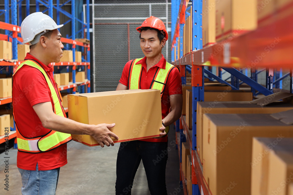 Group of warehouse workers men with hardhats and reflective jackets carrying a large box for delivery to production stock and inventory in retail warehouse logistics, distribution center Group of warehouse workers men with hardhats and reflective jackets carrying a large box for delivery to production stock and inventory in retail warehouse logistics, distribution center