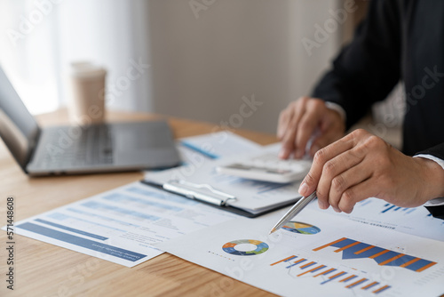 Young Asian businesswoman pointing document data graph and chart paper marketing and investment Statistical profit reports for financial, economic and financial growth. management and planning.
