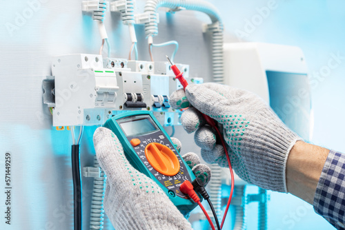 Electrician engineer tests electrical installations and wires in  electical panel.  Electrician measure voltage. photo