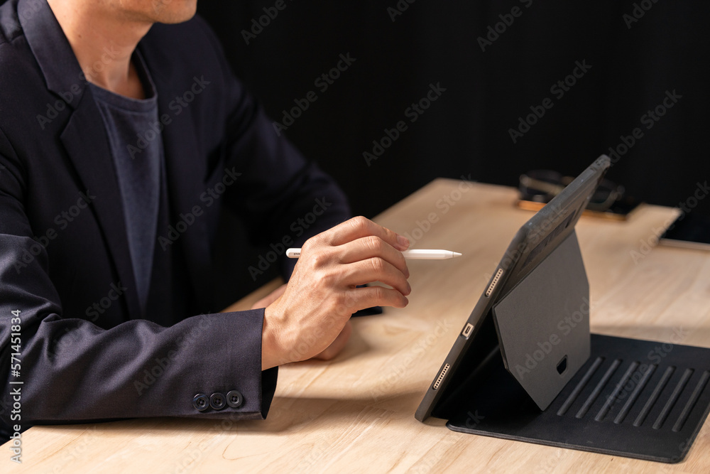 Close up of man using digital tablet, finger touching on screen and working on laptop computer, networking at home office, online working, freelancer at work Close up of man using digital tablet, finger touching on screen and working on laptop computer, networking at home office, online working, freelancer at work