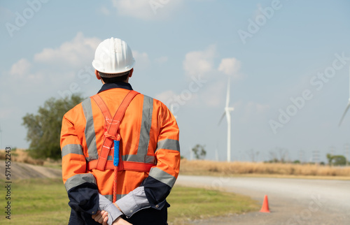 Engineer at Natural Energy Wind Turbine site with a mission to take care of large wind turbines Use a walkie talkie to communicate with a colleague working on top of the wind turbine.